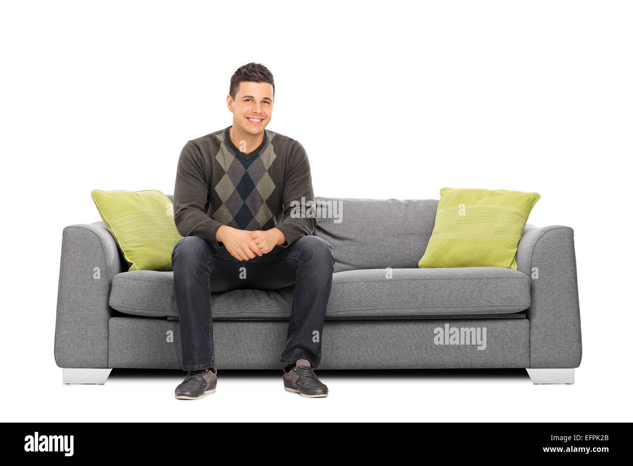Cheerful young man sitting on a modern sofa isolated on white background Stock Photo