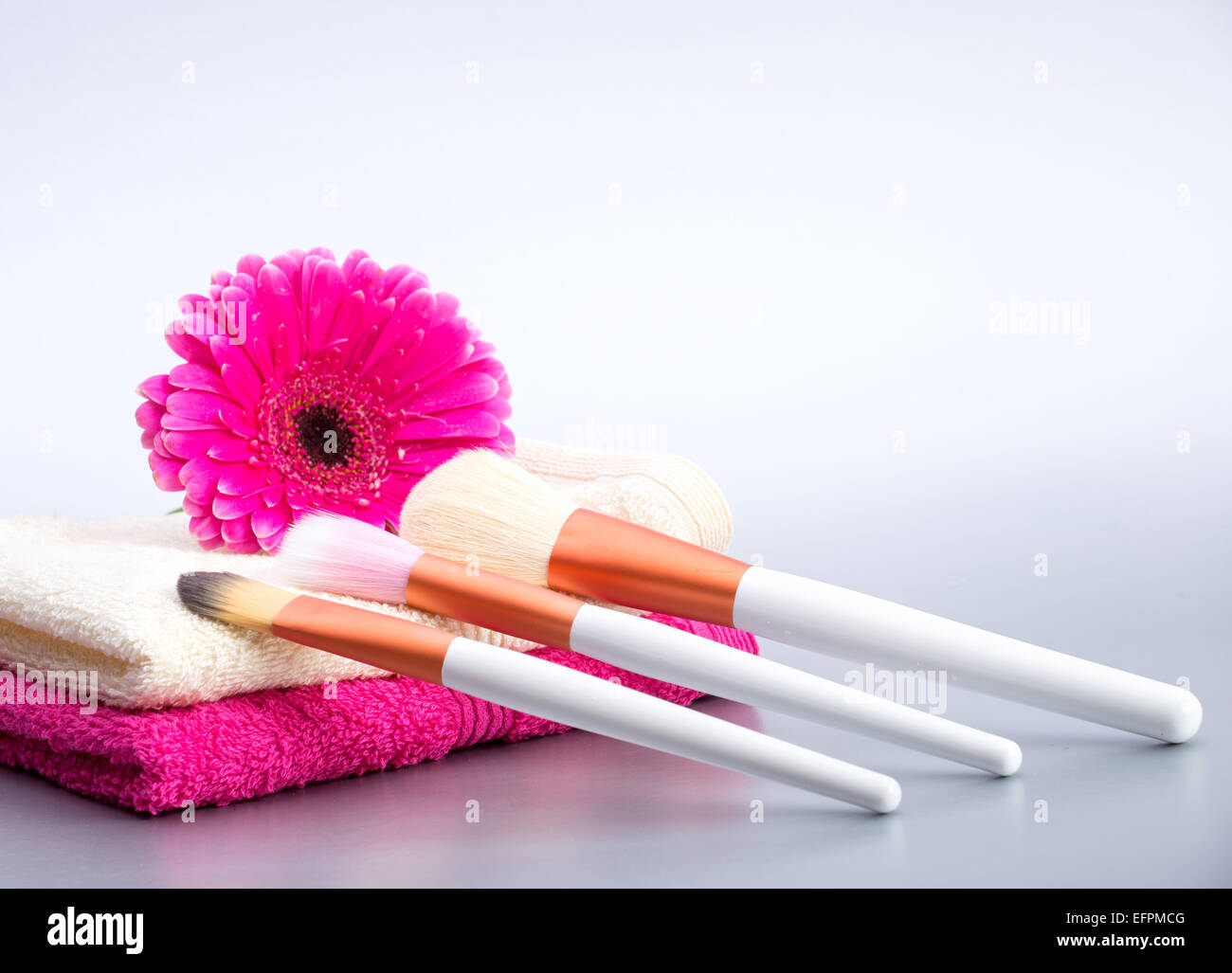 Brushes for make-up  on towel with  big pink flower Stock Photo