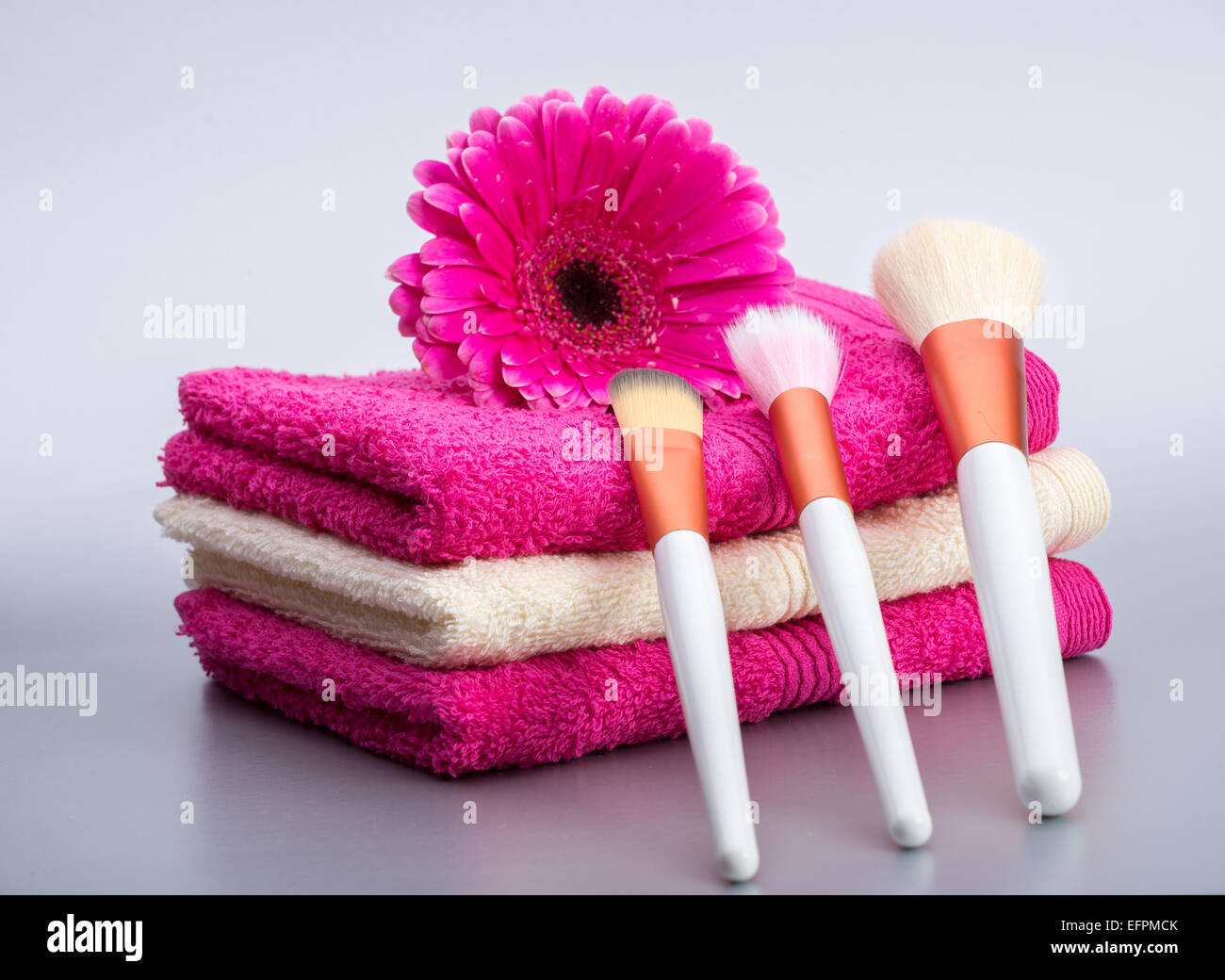 Brushes for make-up  on towel with  big pink flower Stock Photo