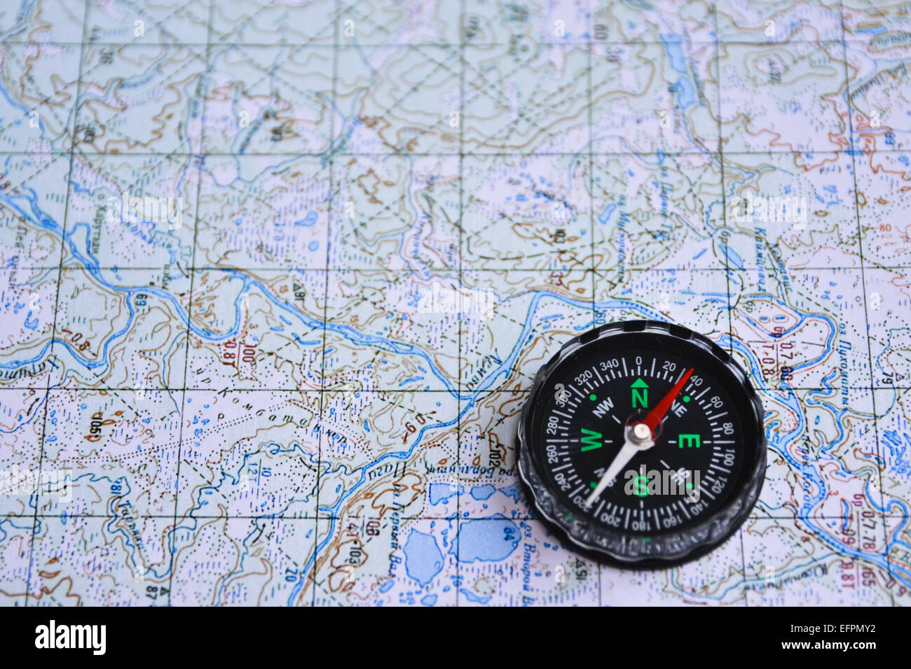 The magnetic compass is located on a topographic map. Equipment for travel - map and compass. Stock Photo