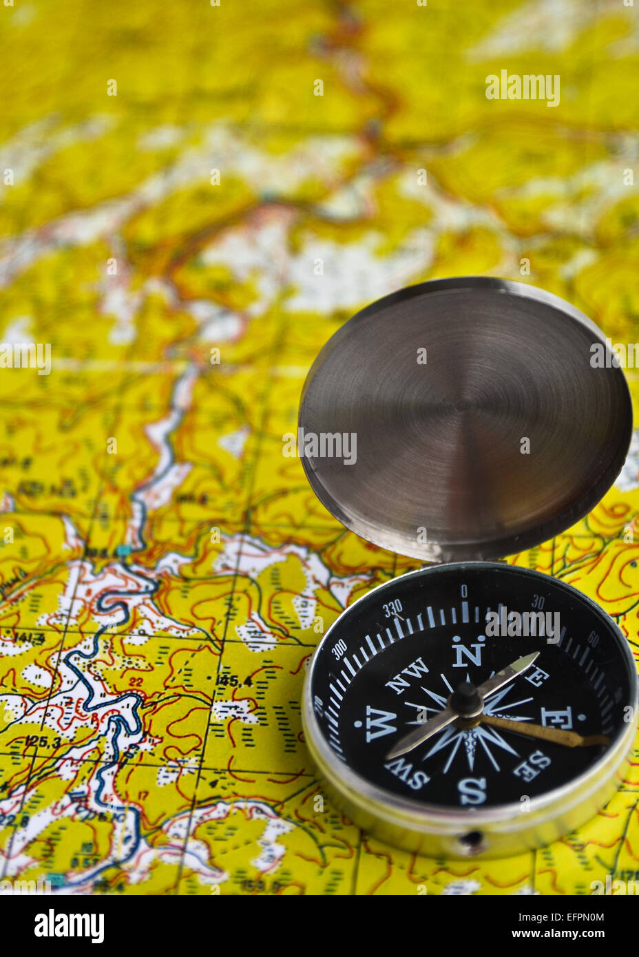 The magnetic compass is located on a topographic map. Satellites adventure - map and compass. Stock Photo