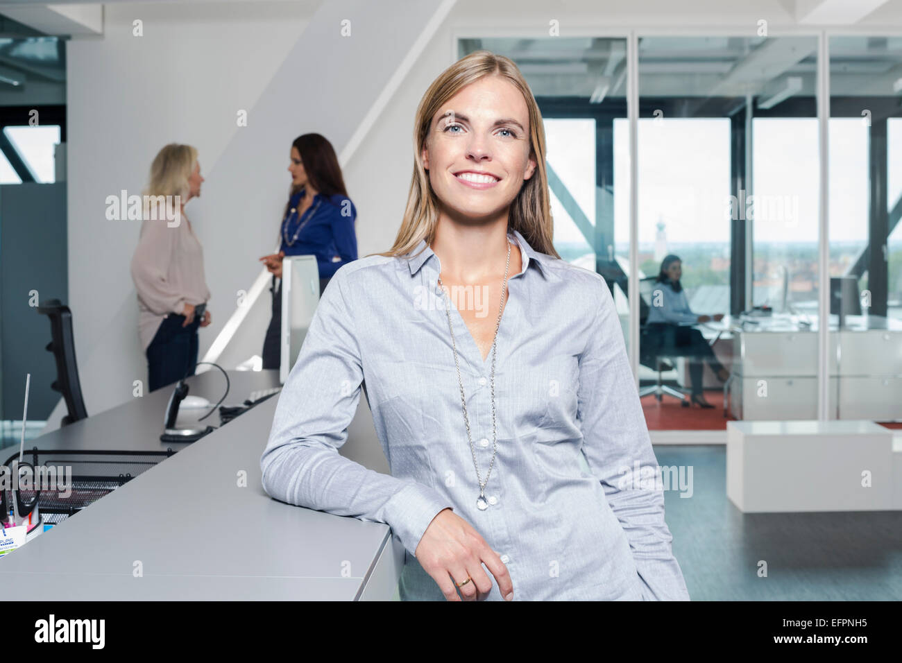 Mature woman wearing grey shirt in office, portrait Stock Photo