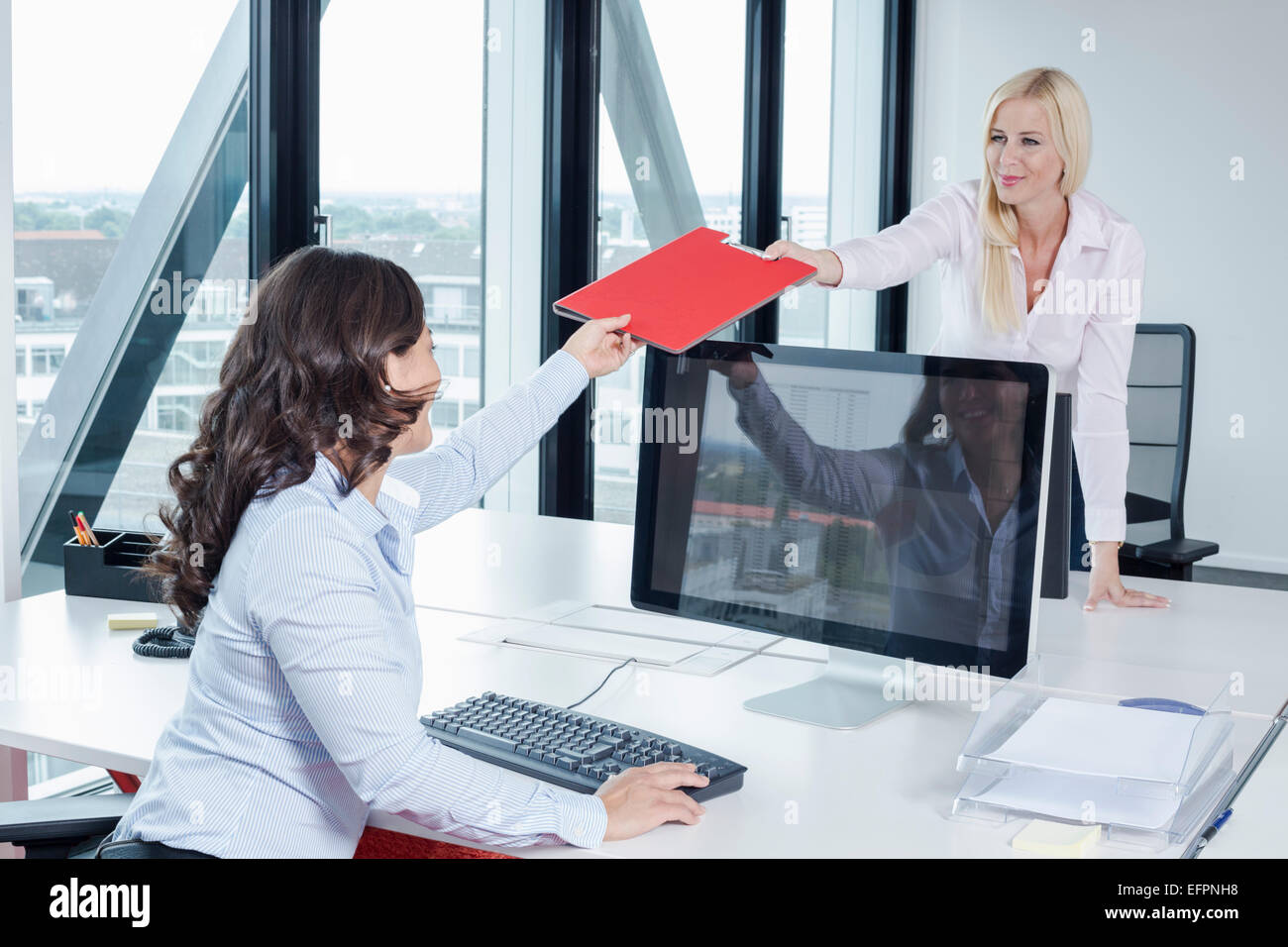 Woman giving colleague file in office Stock Photo