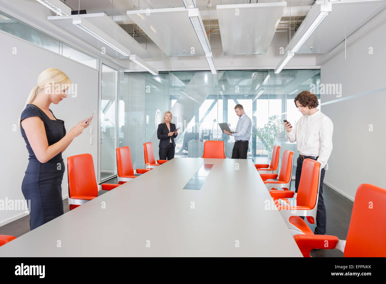 People using digital devices in conference room Stock Photo