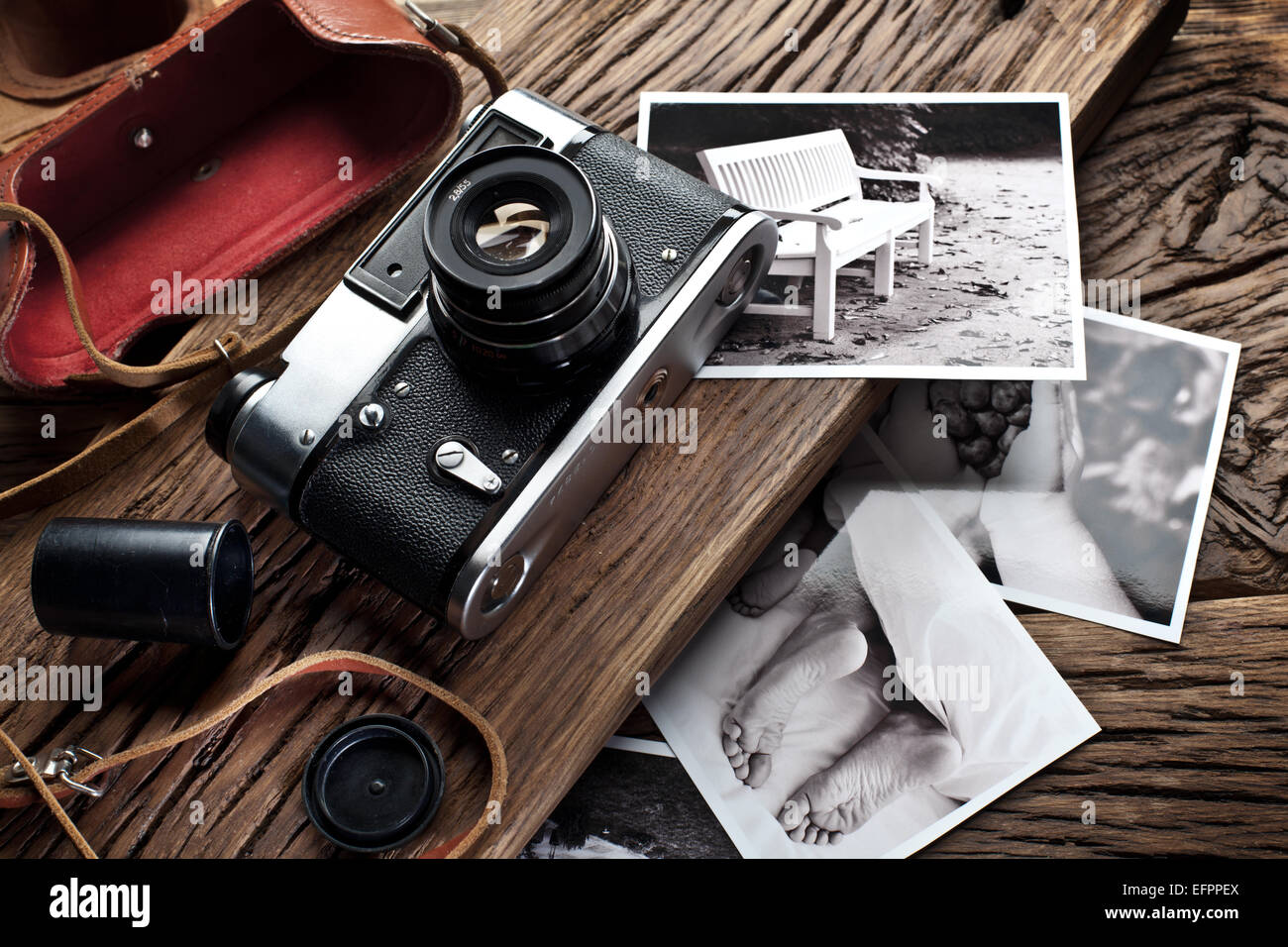 Old range-finder camera and black-and-white photos on the old wooden table. Stock Photo
