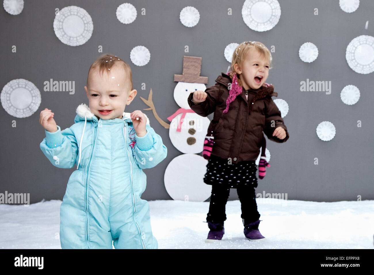 Baby girls with snow and snowman cutouts Stock Photo