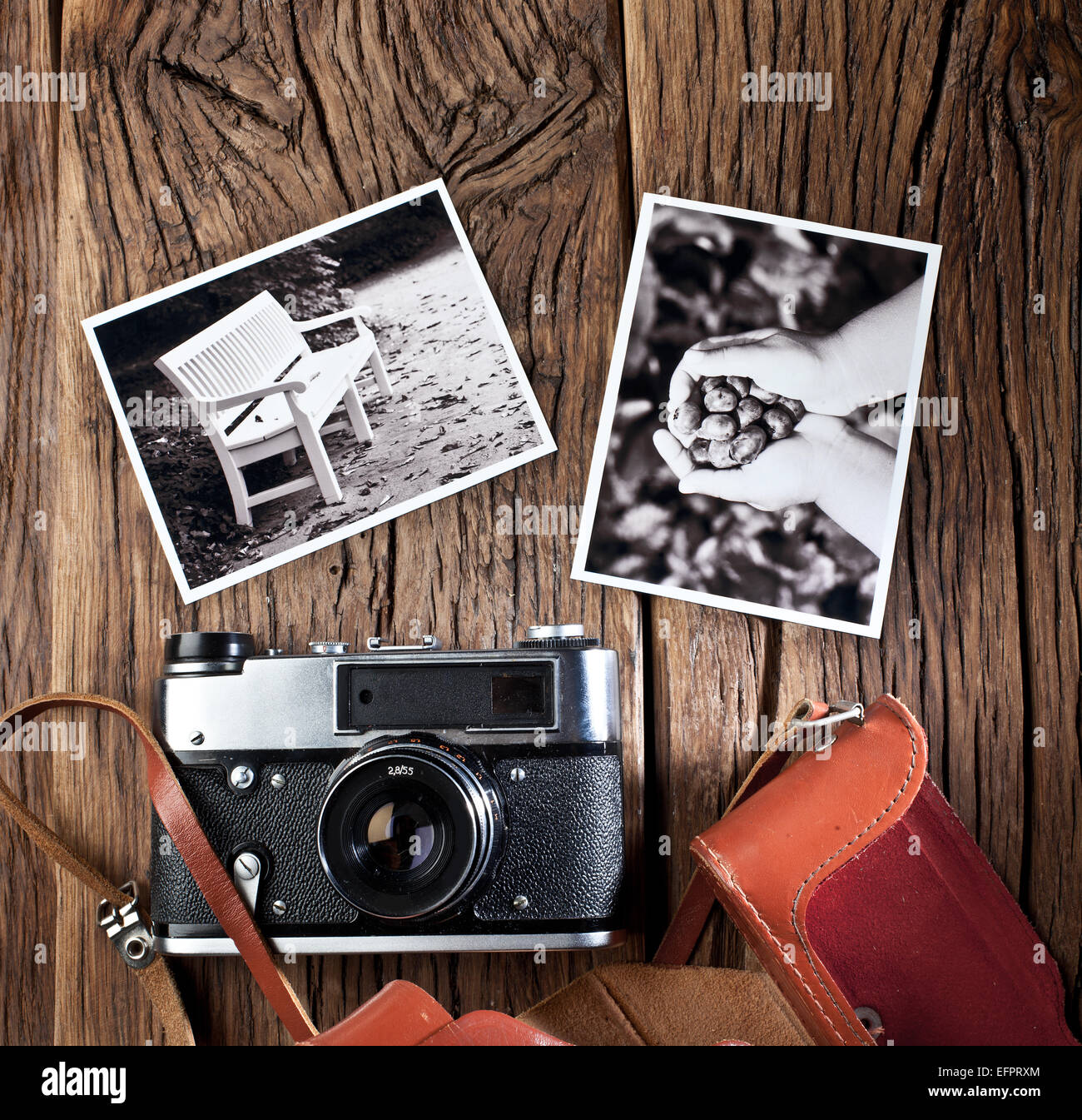 Old rangefinder camera and black-and-white photos on the old wooden table. Stock Photo