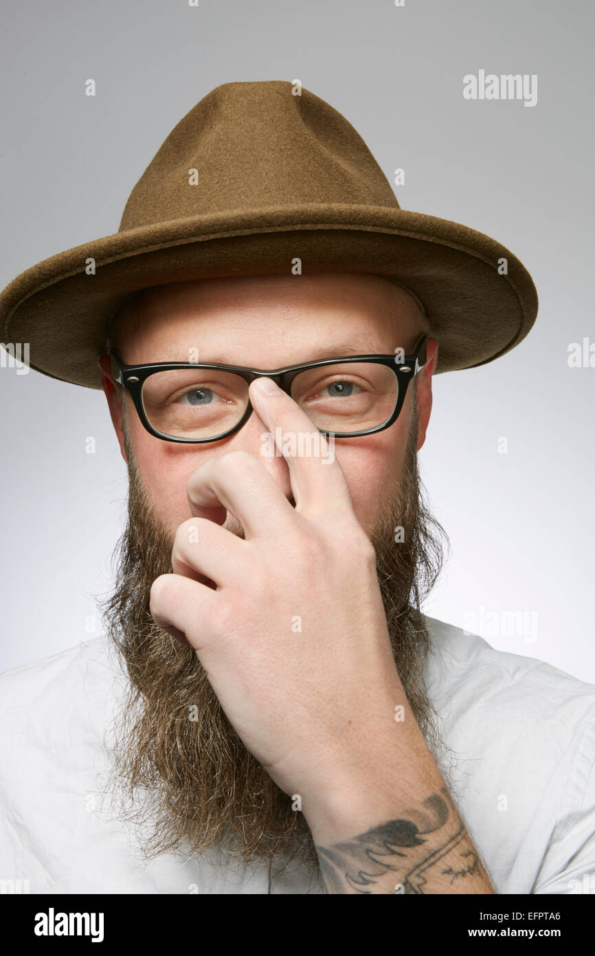 Studio portrait of mid adult man in trilby with hand hiding face Stock Photo