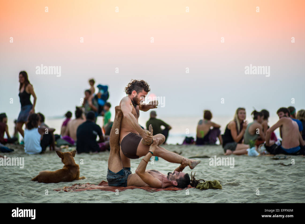A couple doing acroyoga at sunset on the beach of Gokarna, India. Stock Photo