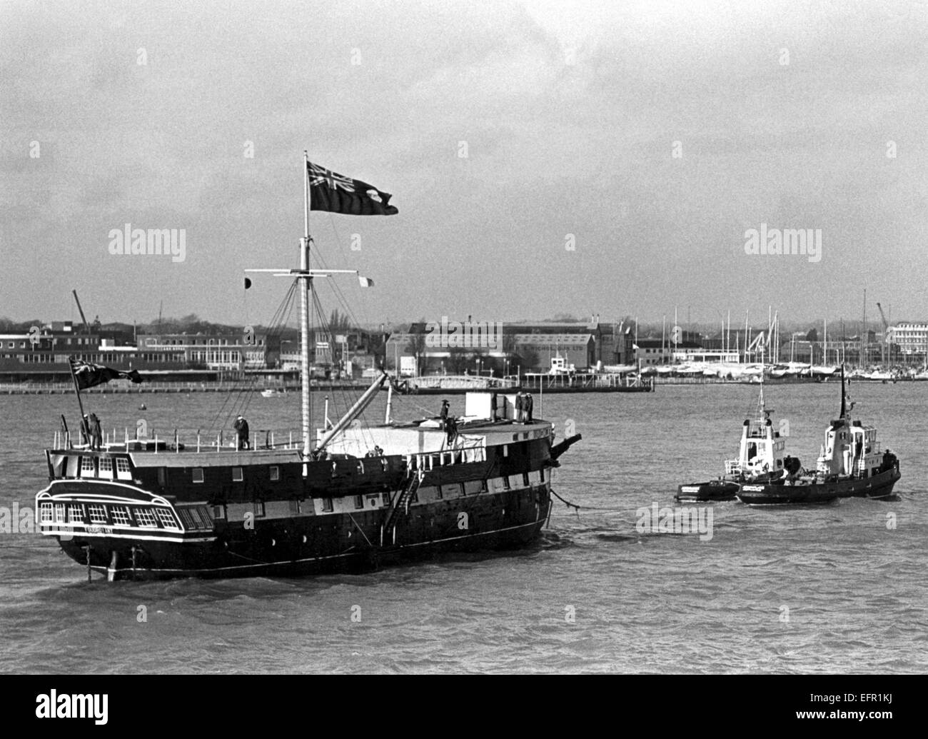 AJAXNETPHOTO. - 21ST JANUARY, 1977. PORTSMOUTH, ENGLAND. - WOODEN WALL RETURNS -  T.S. FOUDROYANT (EX TRINCOMALEE) UNDER TOW ENTERING HARBOUR AFTER RECENT REFIT. PHOTO:JONATHAN EASTLAND/AJAX REF:2772101 Stock Photo