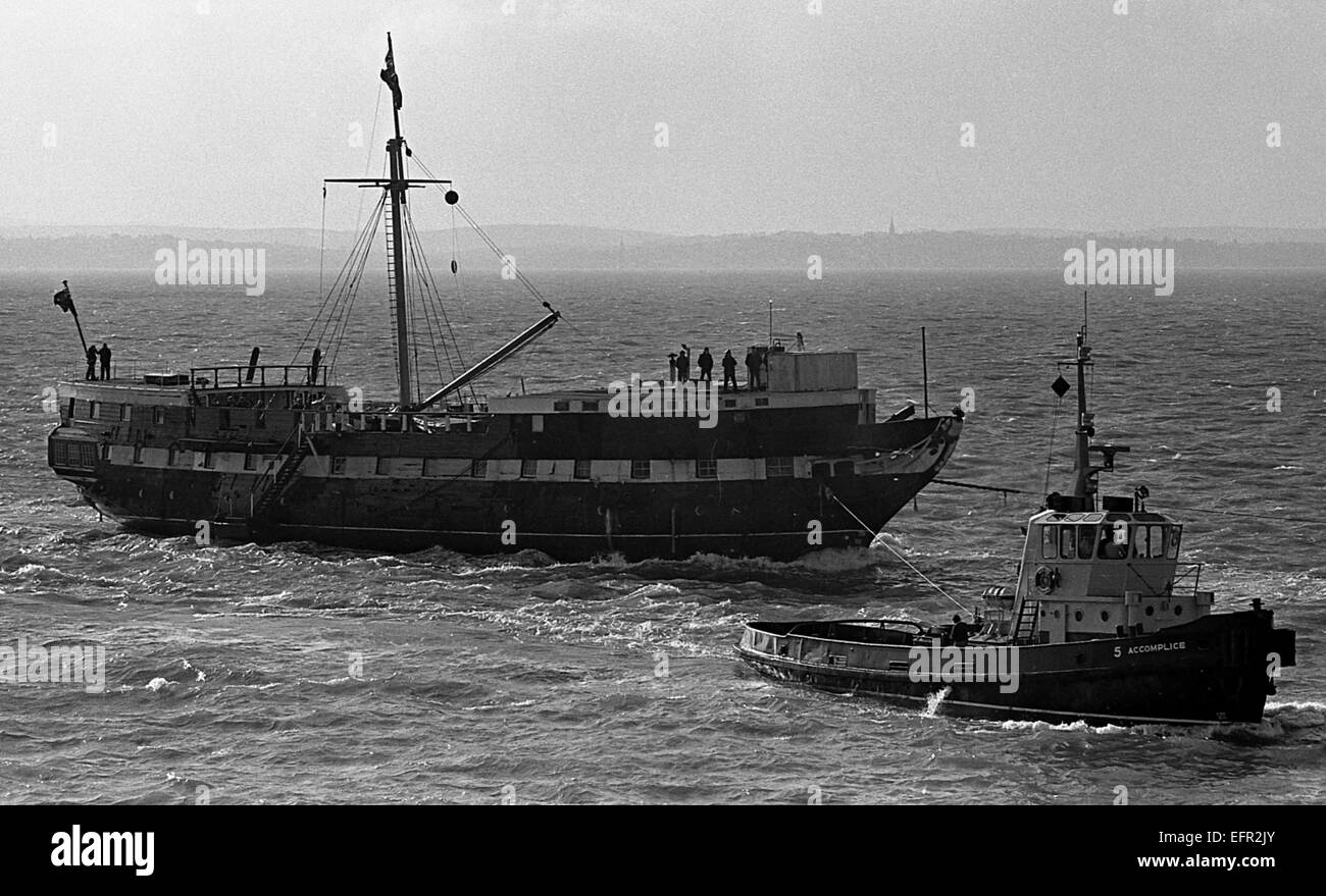 AJAXNETPHOTO. - 21ST JANUARY, 1977. PORTSMOUTH, ENGLAND. - WOODEN WALL RETURNS -  T.S. FOUDROYANT (EX TRINCOMALEE) UNDER TOW ENTERING HARBOUR AFTER RECENT REFIT. PHOTO:JONATHAN EASTLAND/AJAX REF:2772101 25 19 Stock Photo