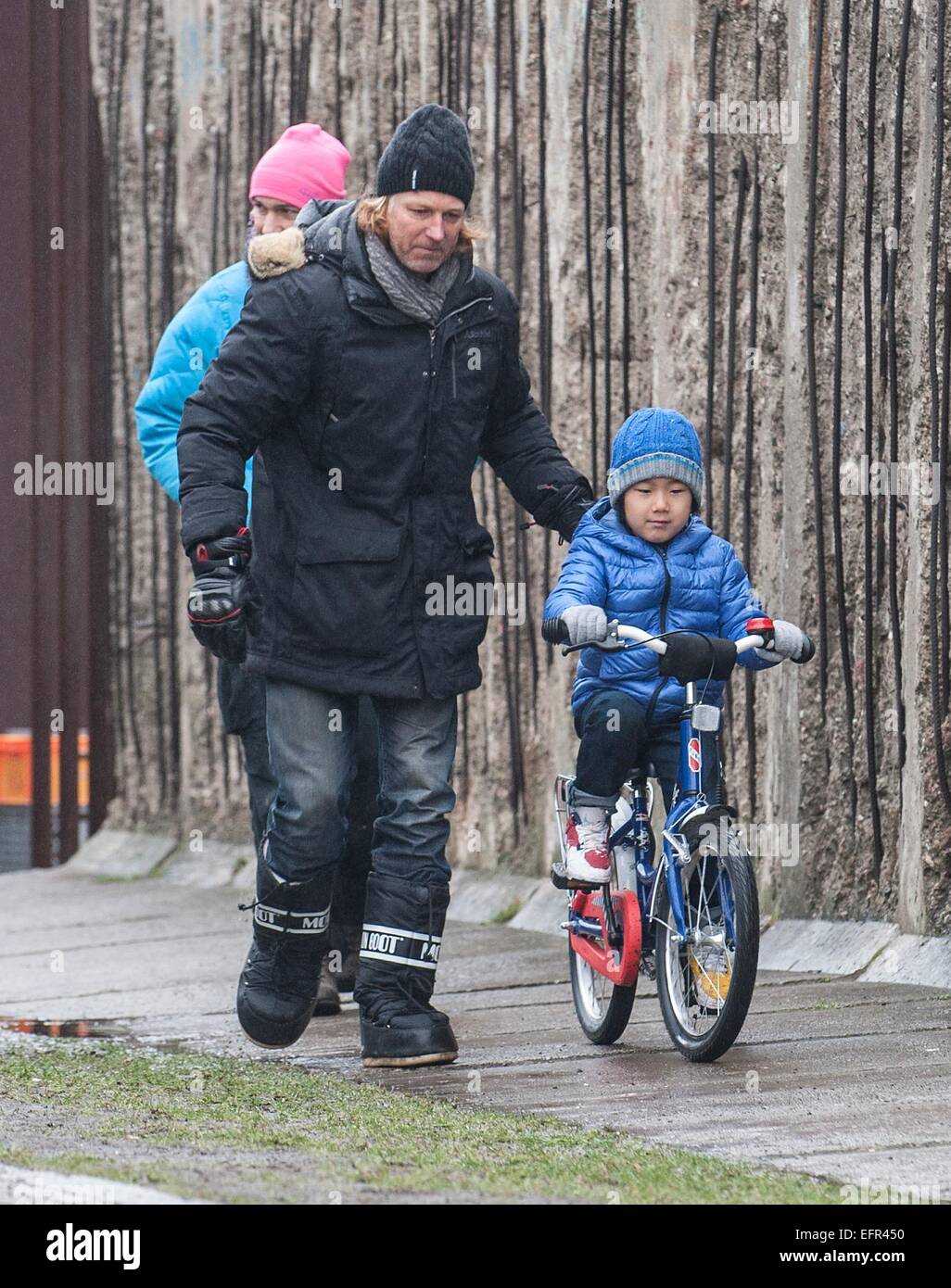 Director and producer Claus Clausen runs next to Lao (6), the son of Chinese artist Ai Weiwei who rides a bike along the Berlin Wall Memorial Bernauer Strasse in Berlin, Germany, 09 February 2015. The boy has the lead role in the short film 'Berlin, I Love You', directed by Ai Weiwei. Because Ai Weiwei can't leave his home country he directs the film via sattelite through multiple skype camera feeds. Photo: Paul Zinken/dpa Stock Photo