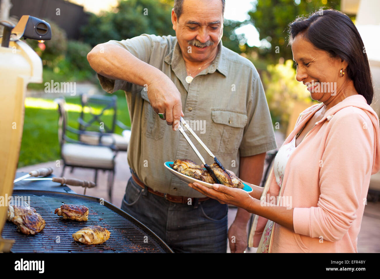 Husband and wife at barbecue grill in garden Stock Photo