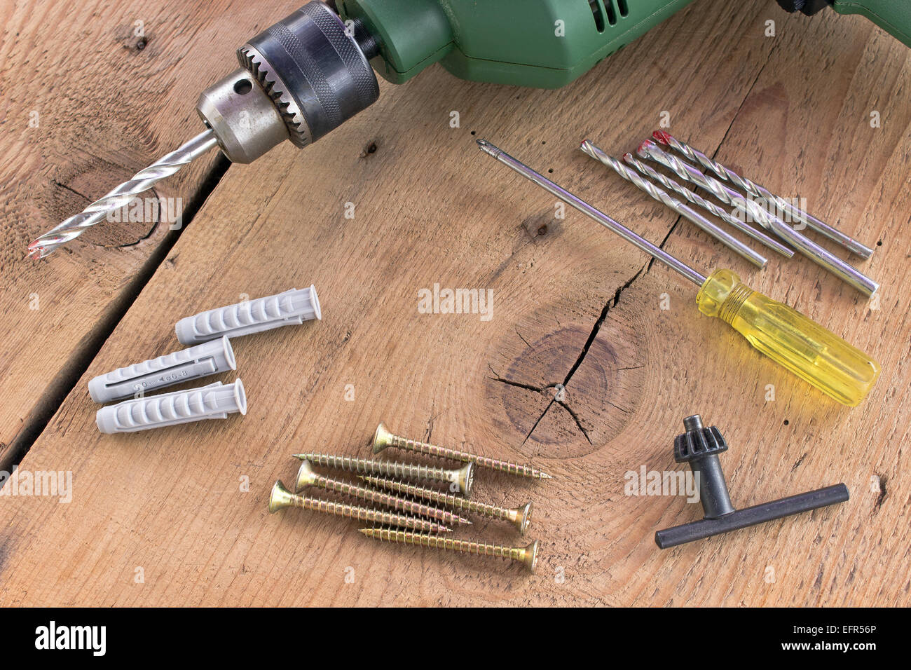 Drill and set of drill bits with screws on wooden background Stock Photo