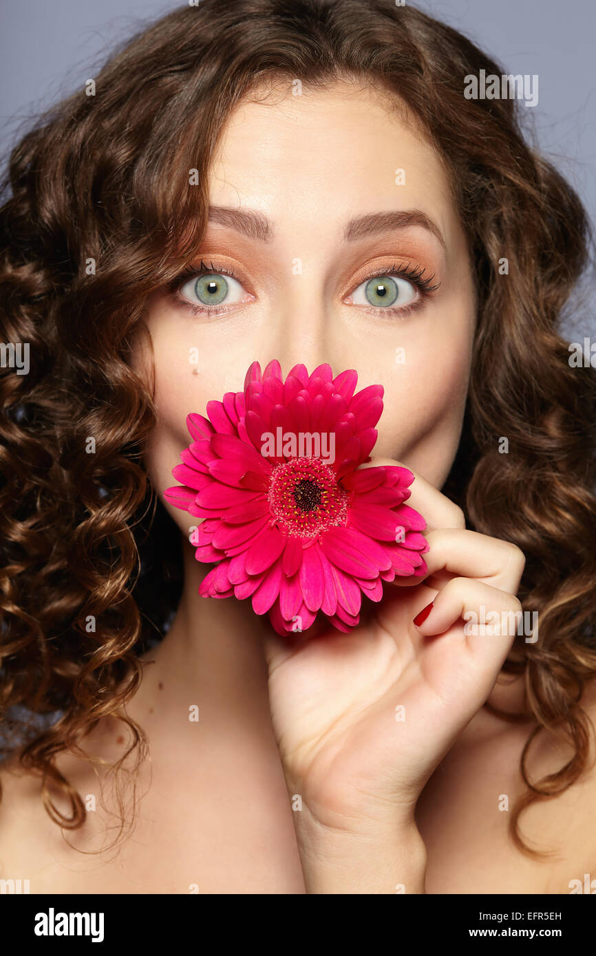 Female model covering mouth with flower Stock Photo