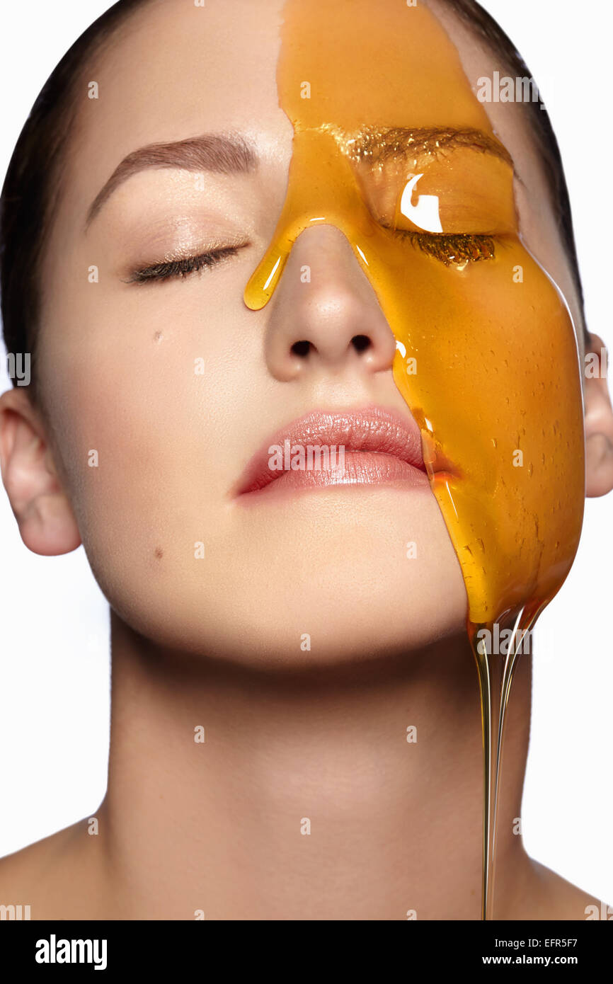 Female model's face partially covered in honey Stock Photo