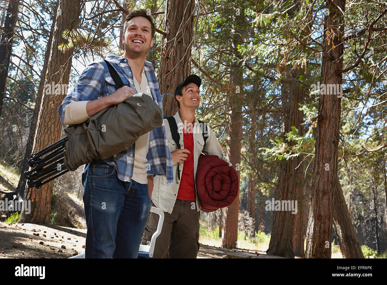 Two young men walking in forest with camping equipment, Los Angeles