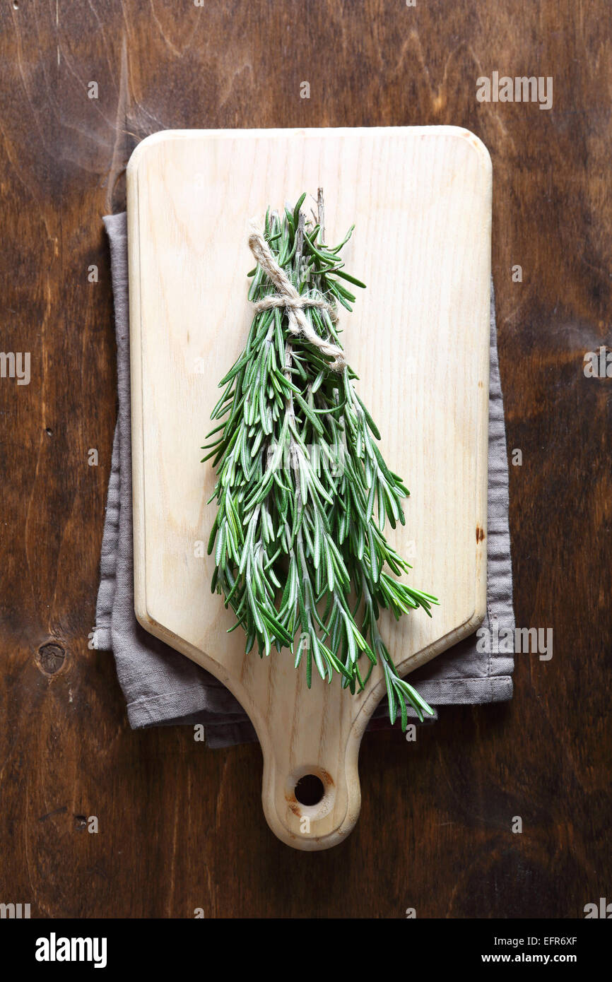 Bunch of rosemary on a cutting board, herb Stock Photo