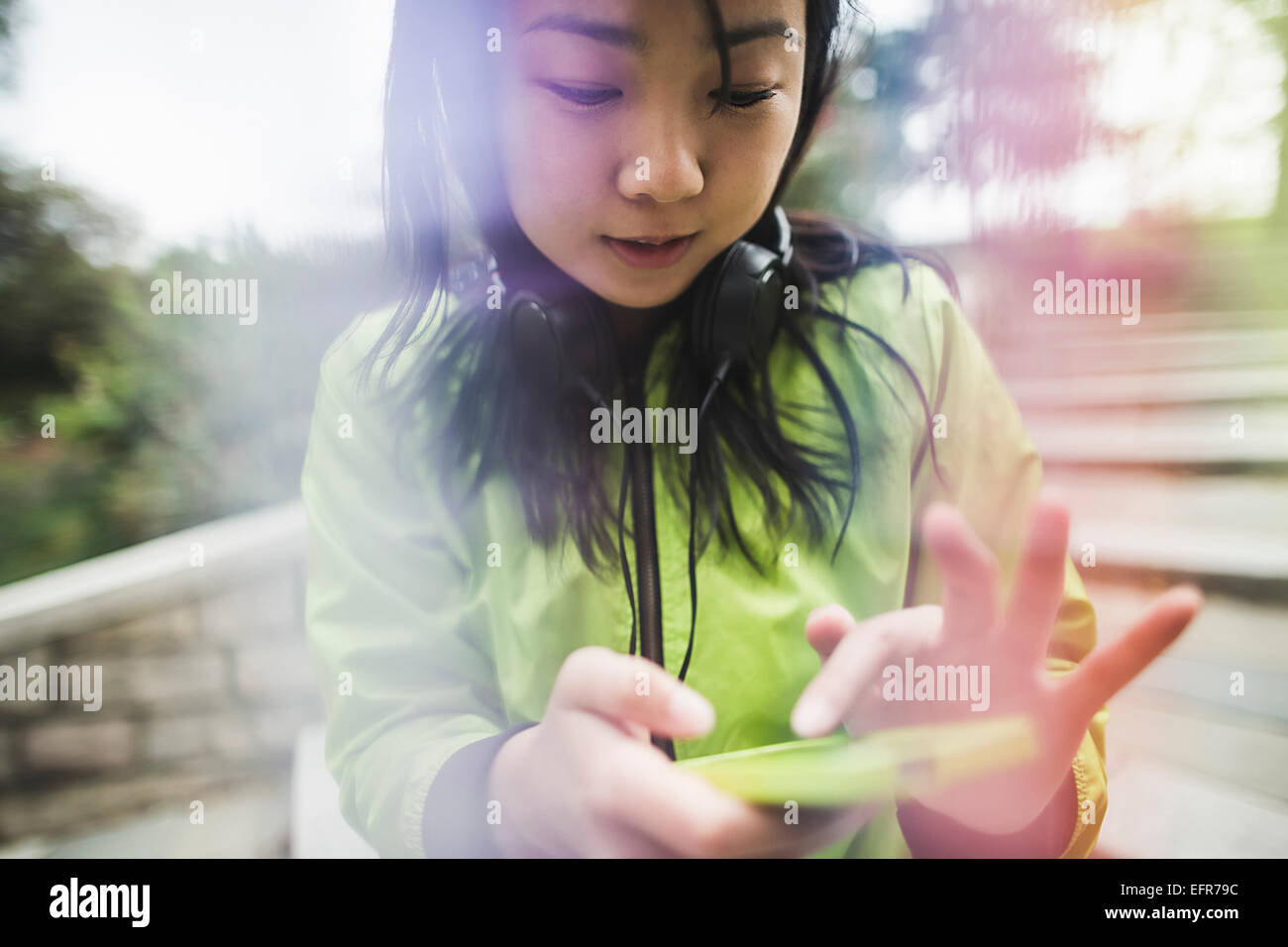 Young woman using mp3 player, wearing headphones, outdoors Stock Photo