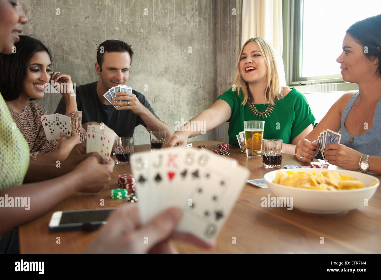 Group of friends playing cards around table Stock Photo
