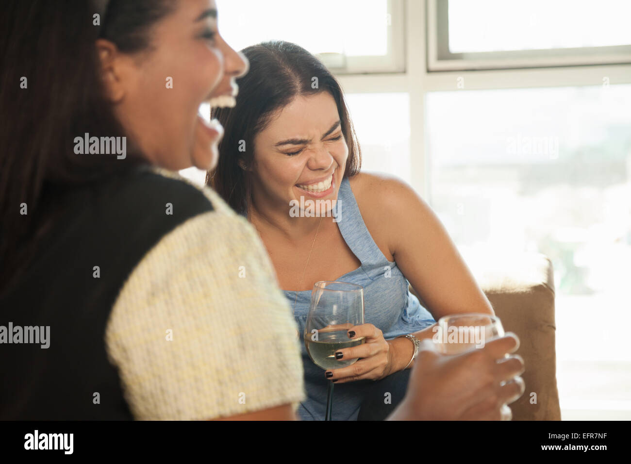 Two female friends sitting on sofa, drinking wine Stock Photo
