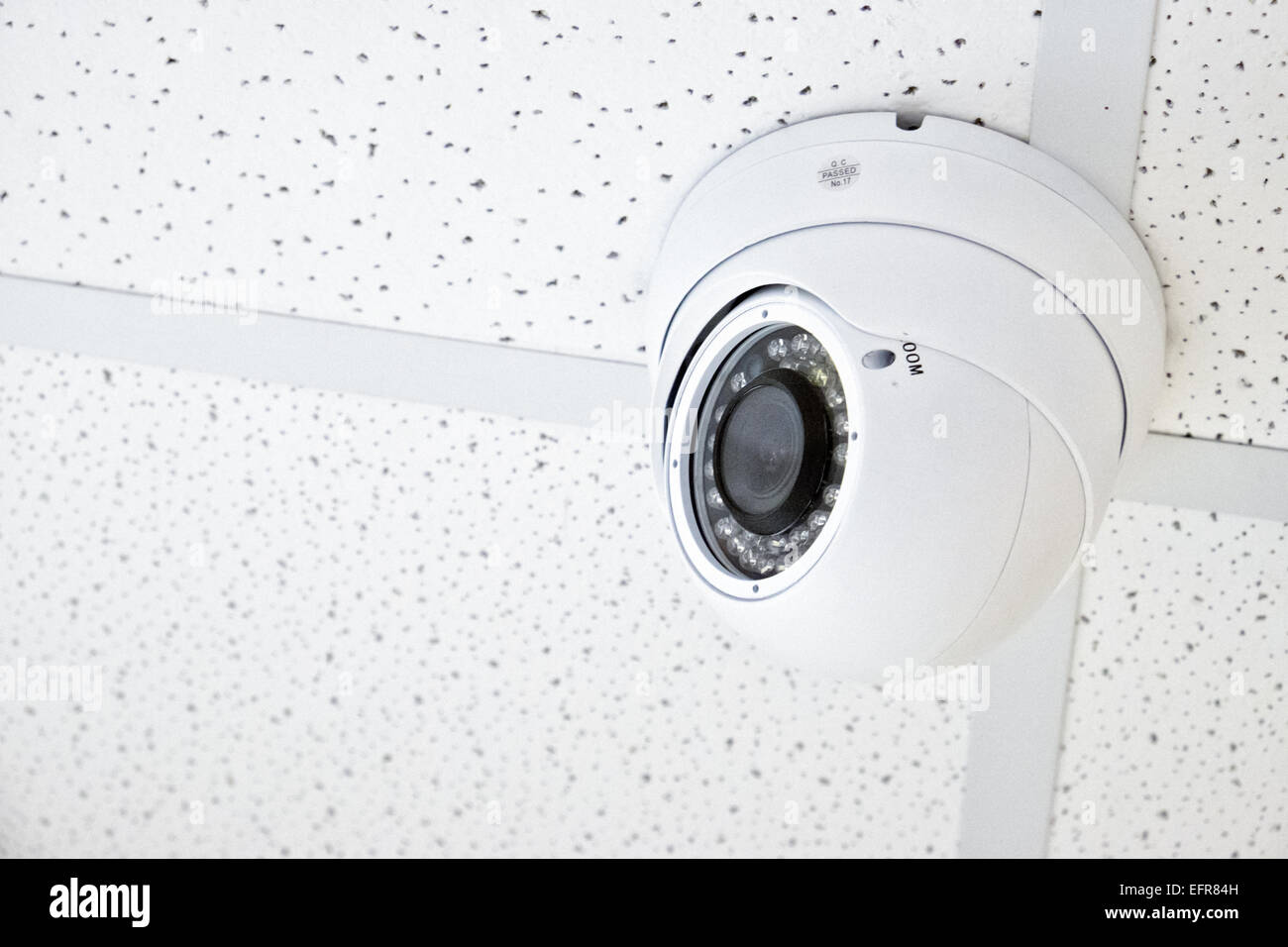 A small infra red capable night vision cctv security camera attached to a ceiling of a retail store Stock Photo