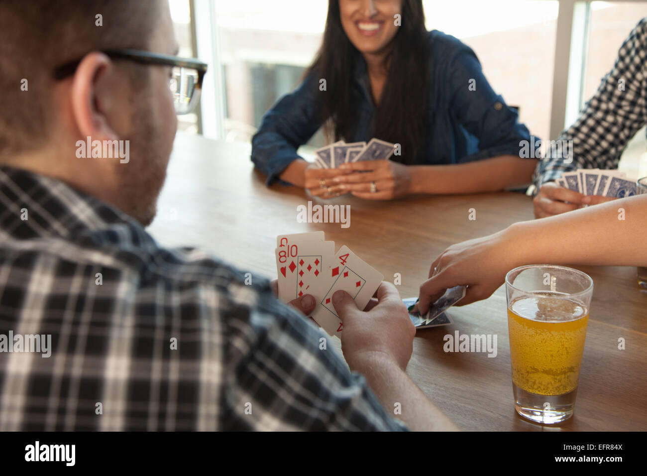 Group of friends playing cards around table Stock Photo