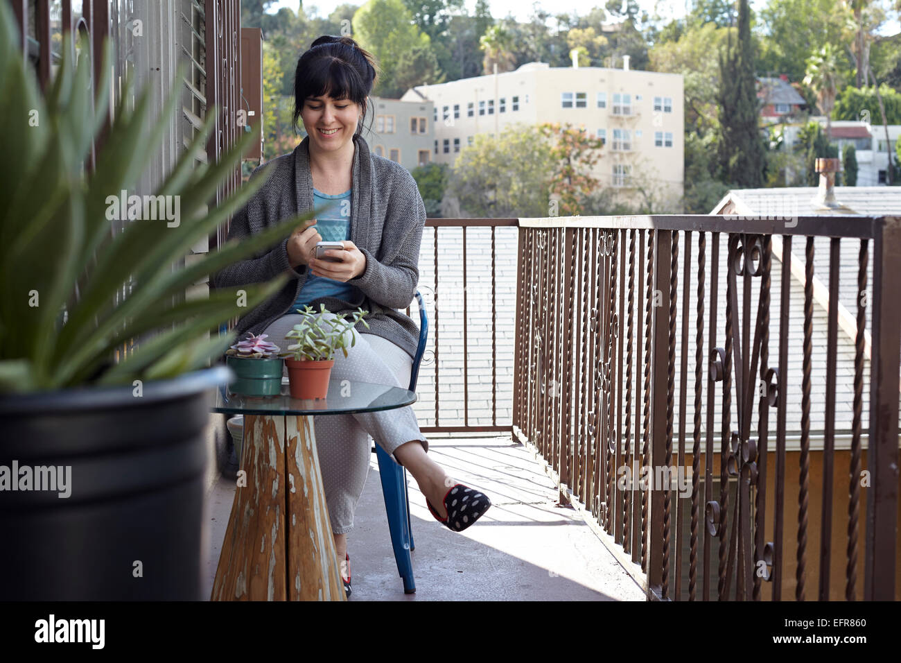 Woman using smartphone on balcony Stock Photo