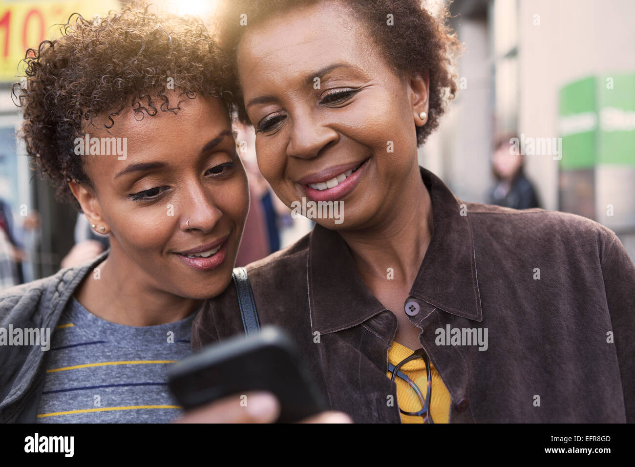 Close up of two mature female friends reading smartphone texts on street Stock Photo