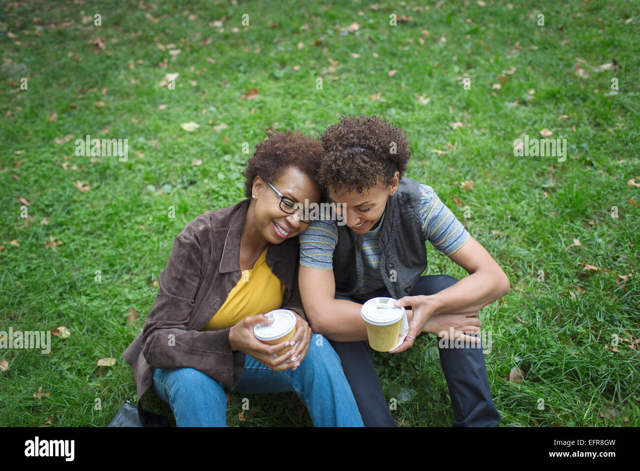 Two mature female friends drinking takeaway coffee in park Stock Photo