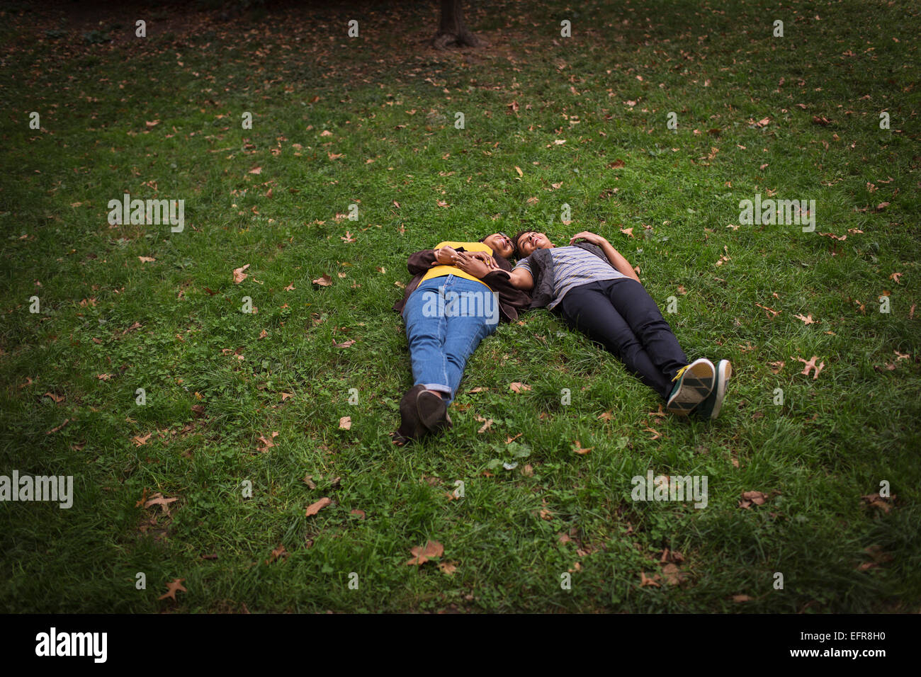 Two mature female friends lying on park grass head to head Stock Photo