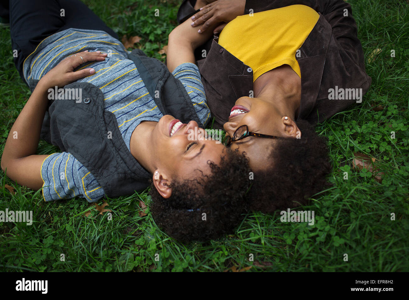 Two mature female friends lying on park grass Stock Photo