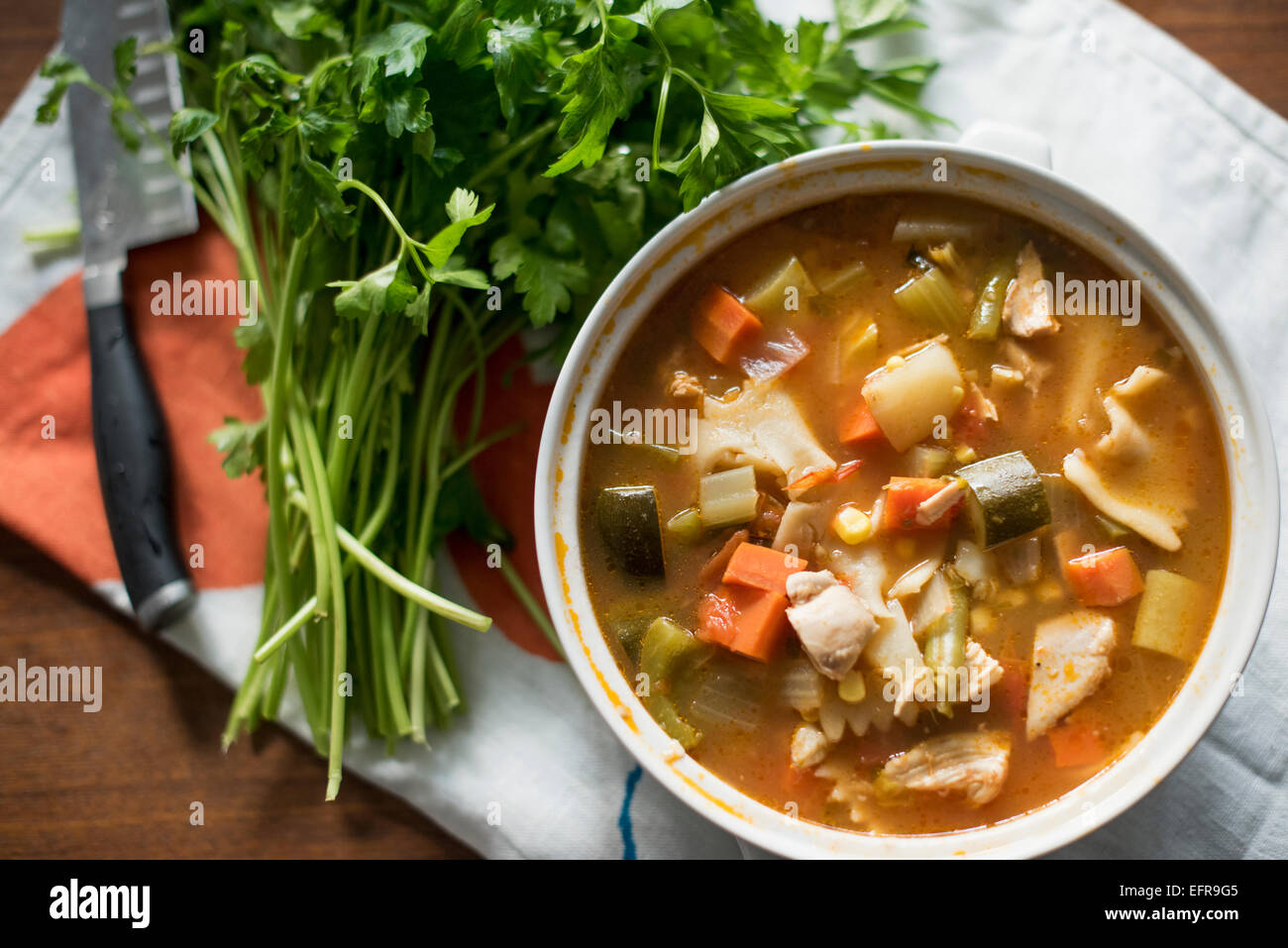 A bowl of vegetable stew and a bunch of fresh herbs on a table Stock Photo Alamy