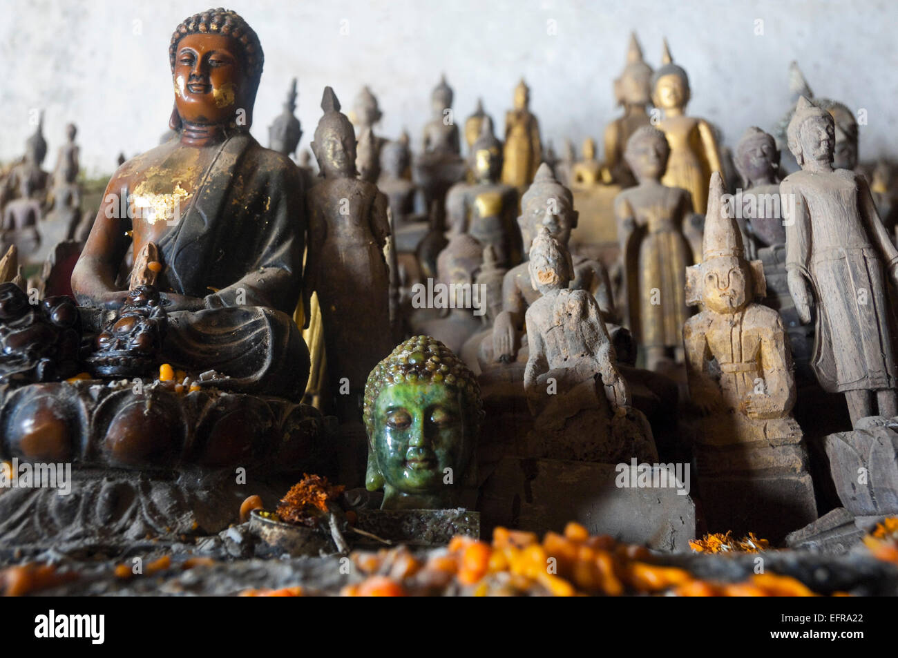 Horizontal close up of hundreds of Buddha statues in Pak Ou or Tam Ting caves on a sunny day. Stock Photo