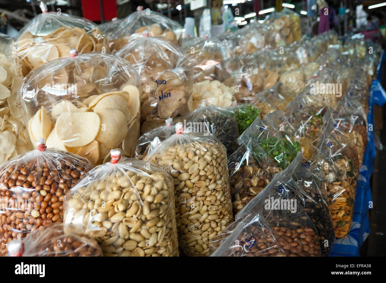 Horizontal close up of rows of plastic bags full of nuts and dried snacks in Thailand. Stock Photo