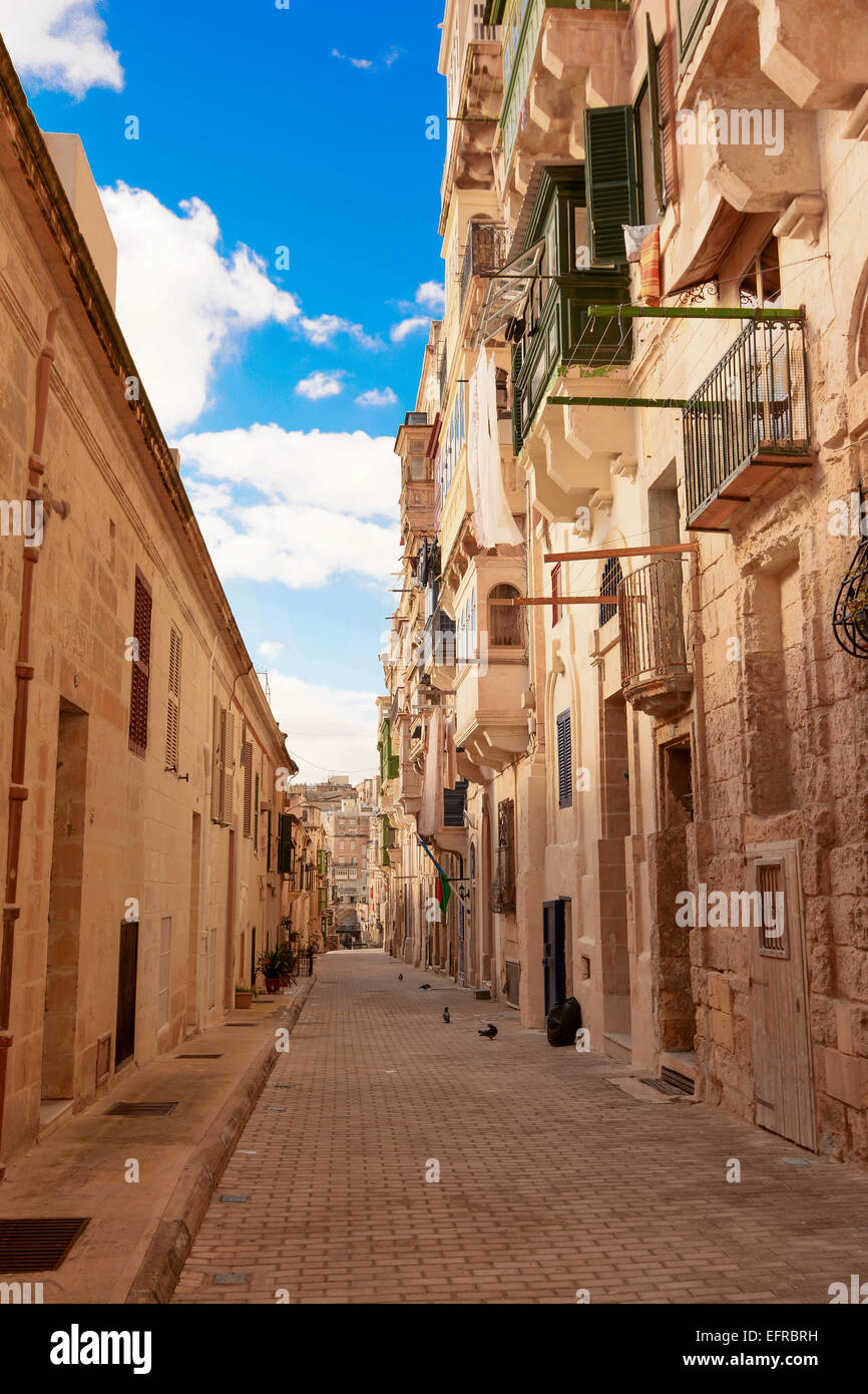 Maltese narrow street in Valetta with stone buildings in traditional architecture Stock Photo