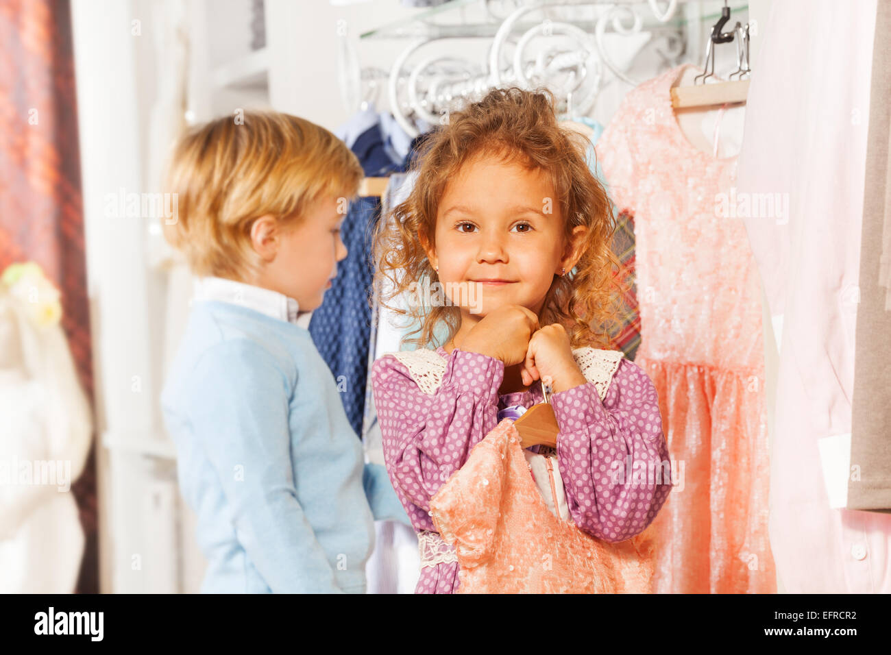 Girl with dress and boy behind choosing clothes Stock Photo