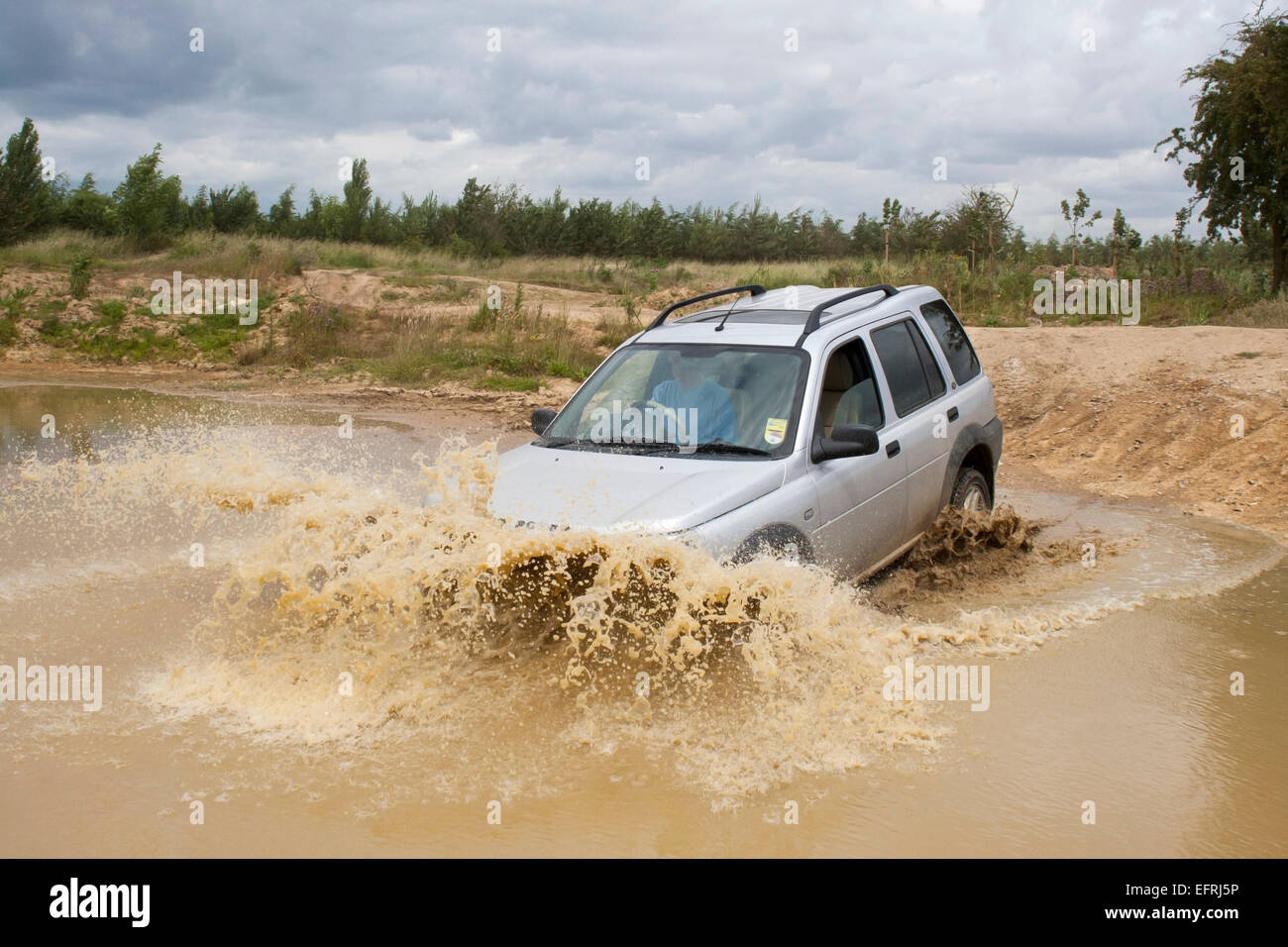 Land rover freelander driving through water and mud - Stock Image