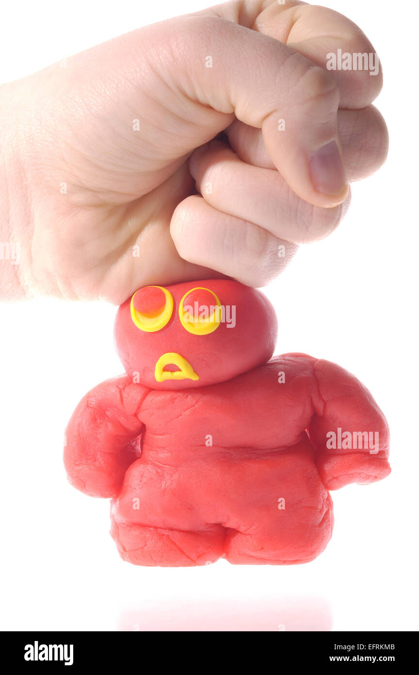 Small clay person getting squashed by a comparatively giant human hand.  Conceptual Stock Photo