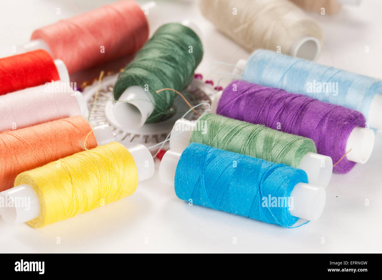 Sewing strings and needles on a light background Stock Photo - Alamy