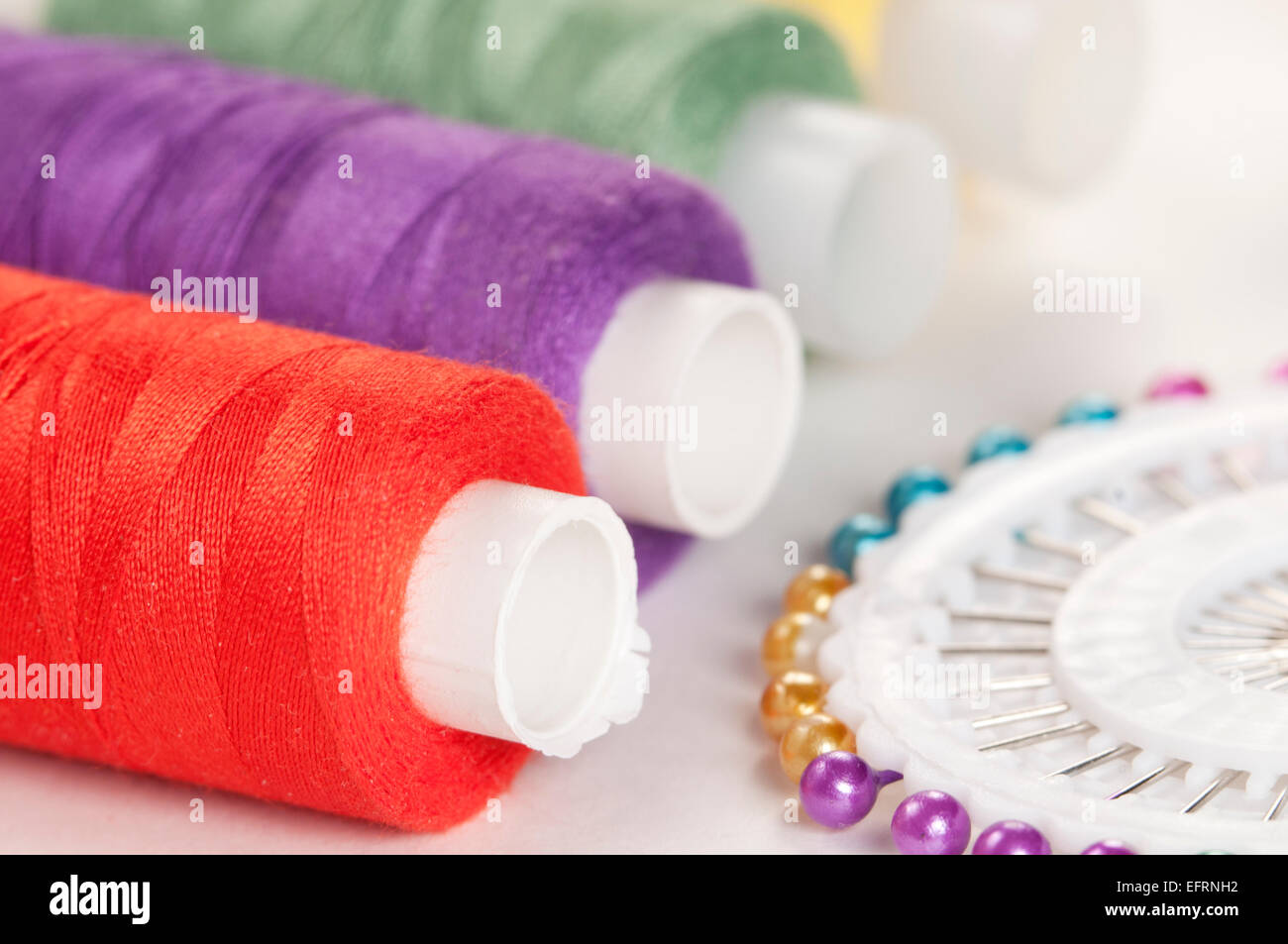 Sewing strings and needles on a light background Stock Photo - Alamy