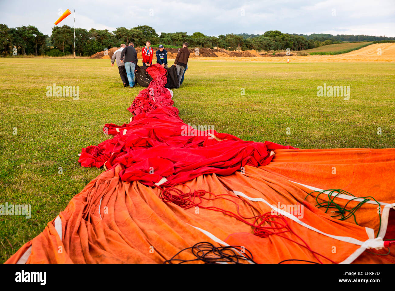 Crew preparing red hot air balloon envelope on airfield, South Oxfordshire, England Stock Photo