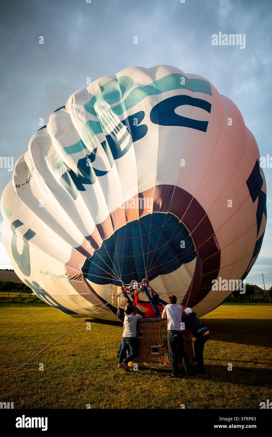 Crew inflating hot air balloon at sunset, South Oxfordshire, England Stock Photo