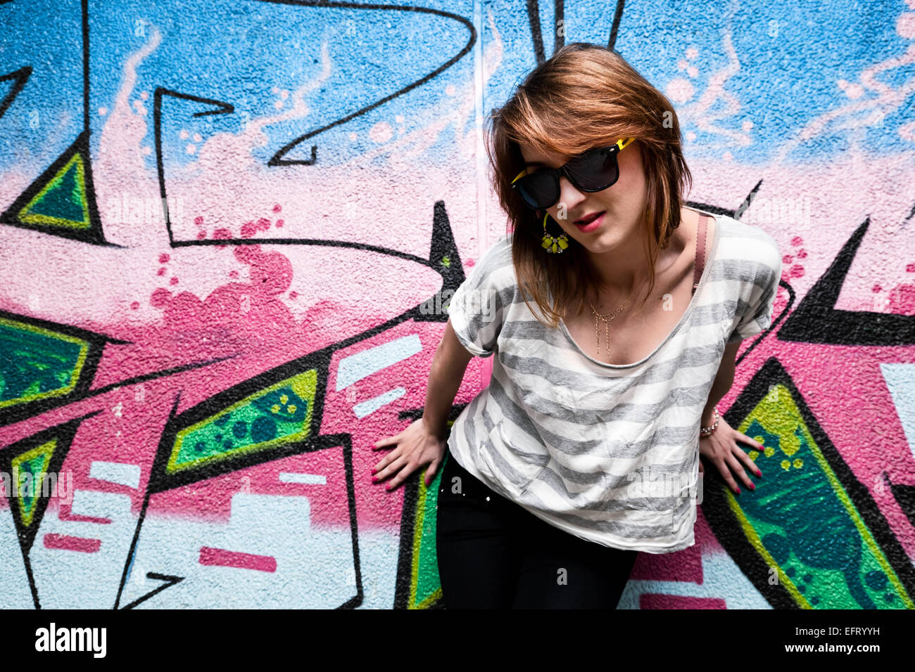 Stylish fashionable girl portrait against colorful graffiti wall. Fashion, trends, subculture. Stock Photo