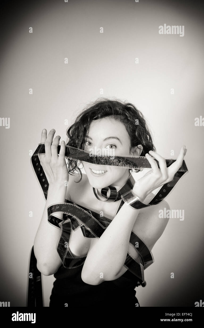 Smiling actress with movie filmstrip covering her nose, vintage black and white effect, vertical portrait Stock Photo