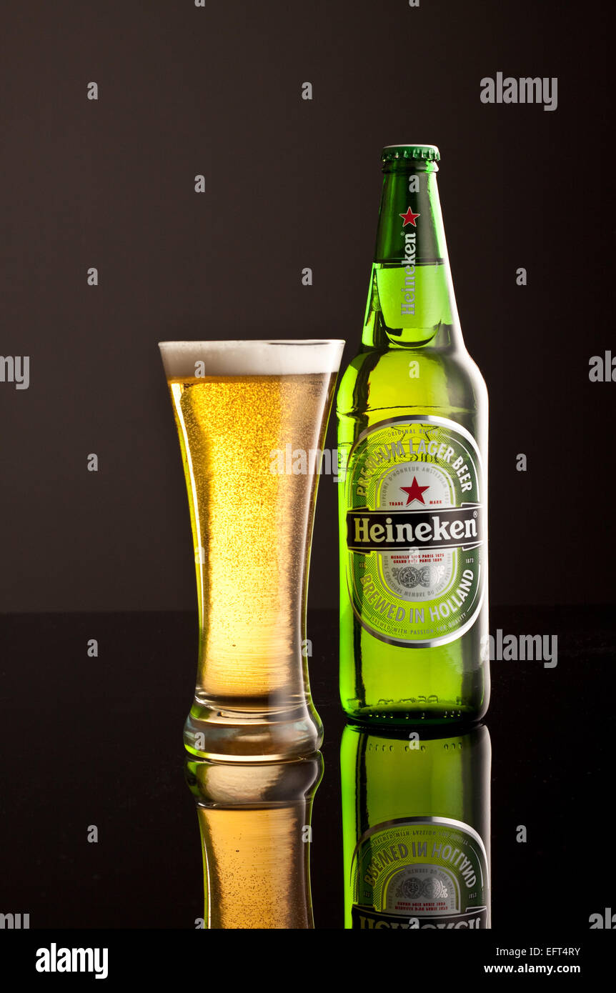 Heineken Lager bottle with glass and frothy head. Stock Photo