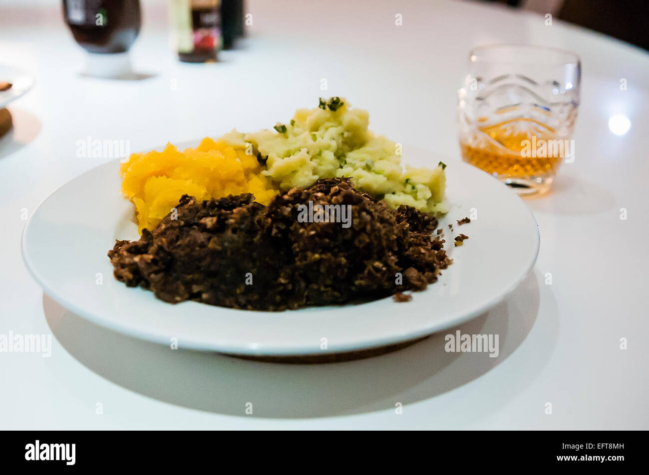 Haggis, neeps (turnips) and tatties (potatoes) with a glass of whisky on Burns night. Stock Photo