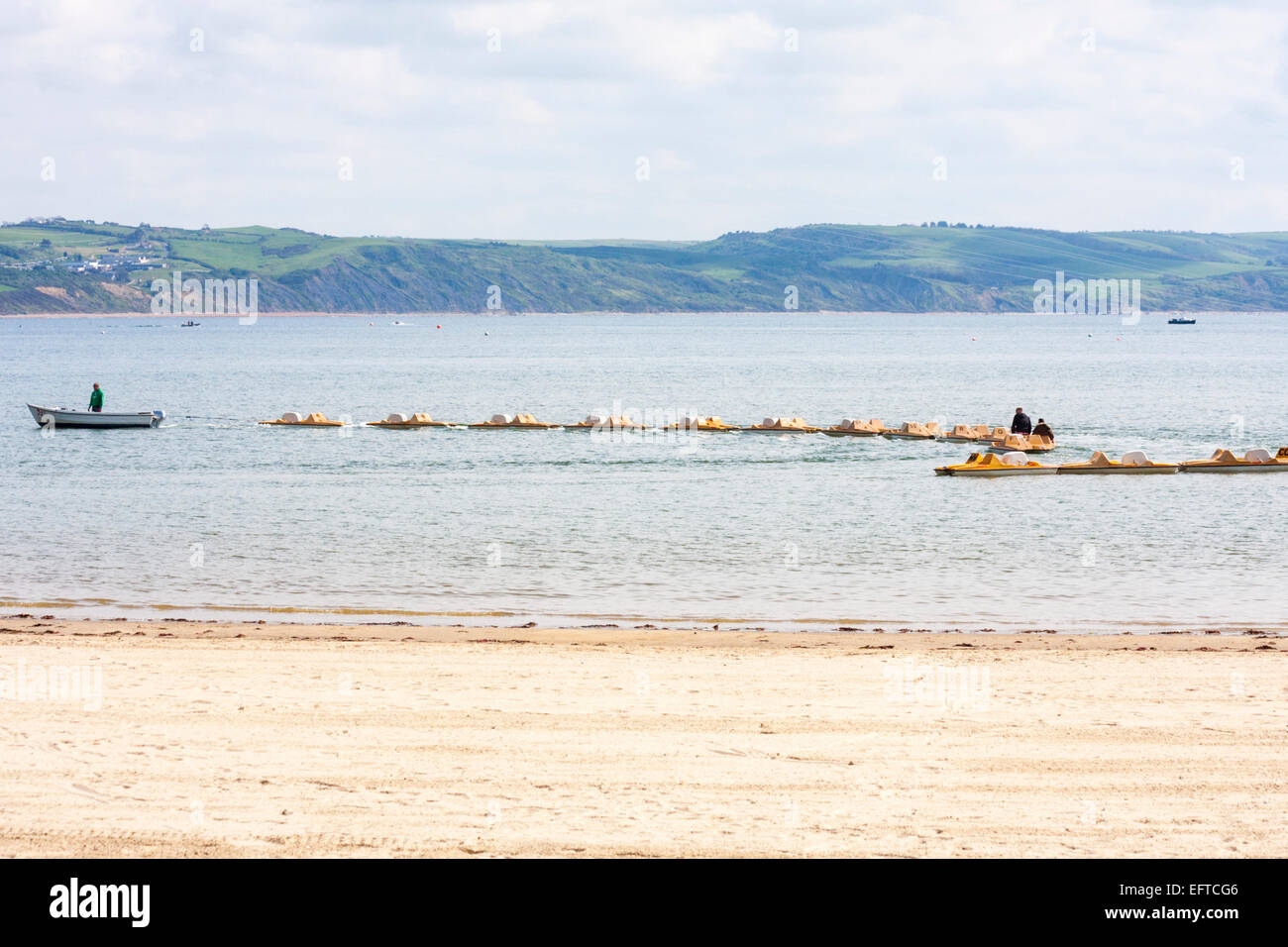 boat towing row of pedalos in the sea at Weymouth beach with the Dorset
