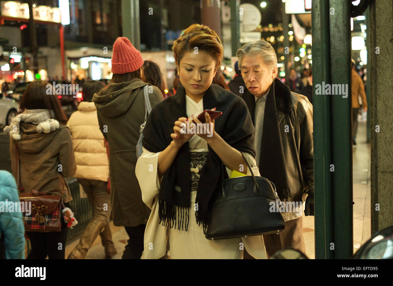Woman dressed in a kimono on her smart phone in the busy shopping district of Shijo Kawaramachi. Kyoto, Japan. Stock Photo