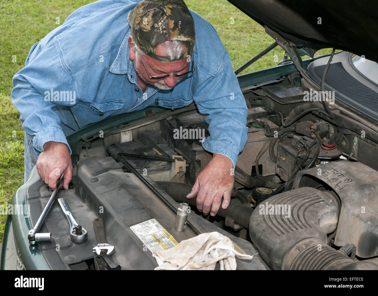 Man working on repairing his vehicle at home. Stock Photo